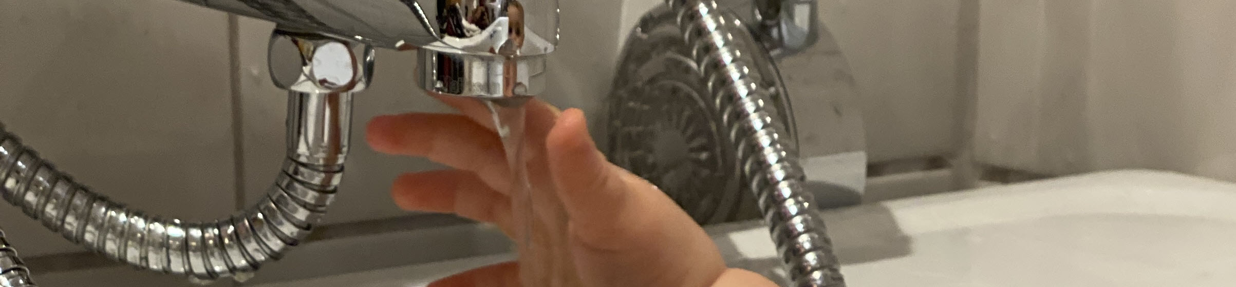 barnehånd tar på vann fra kran i badekar